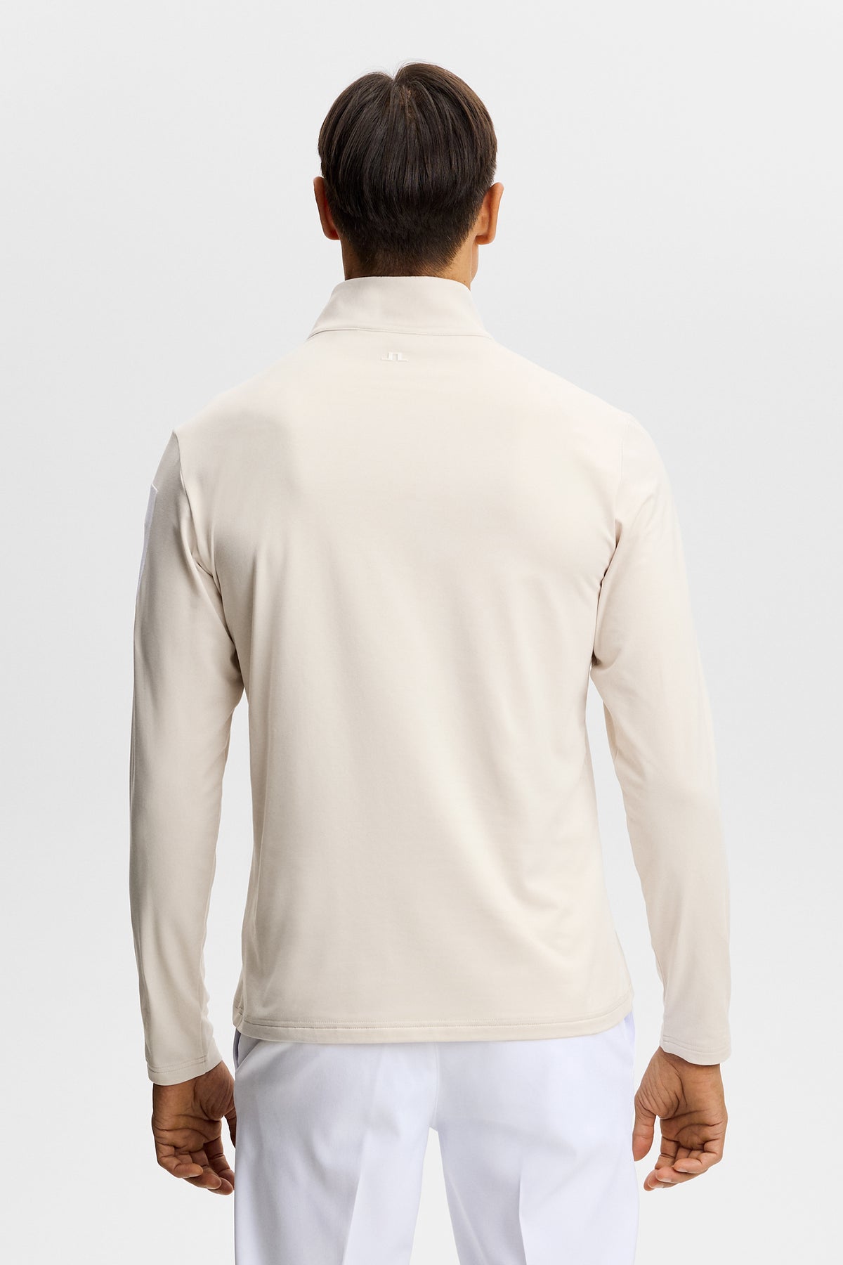 Capa intermedia J.Lindeberg Keaton Quarter Zip Moonbeam: detalle del estampado de goma en la manga y de la cremallera de un cuarto