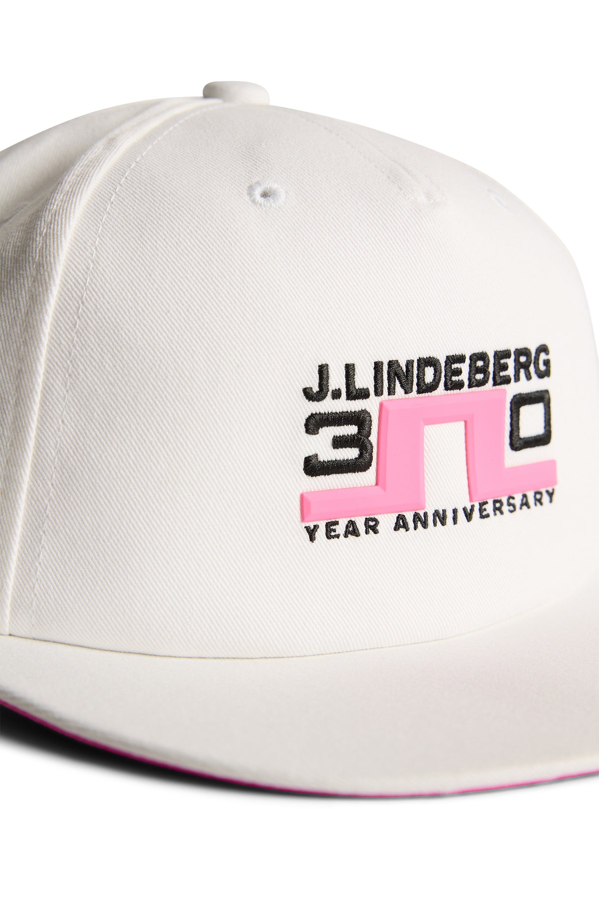 Gorra J.Lindeberg 30Y Cap White: detalle de marca llamativo bajo la visera
