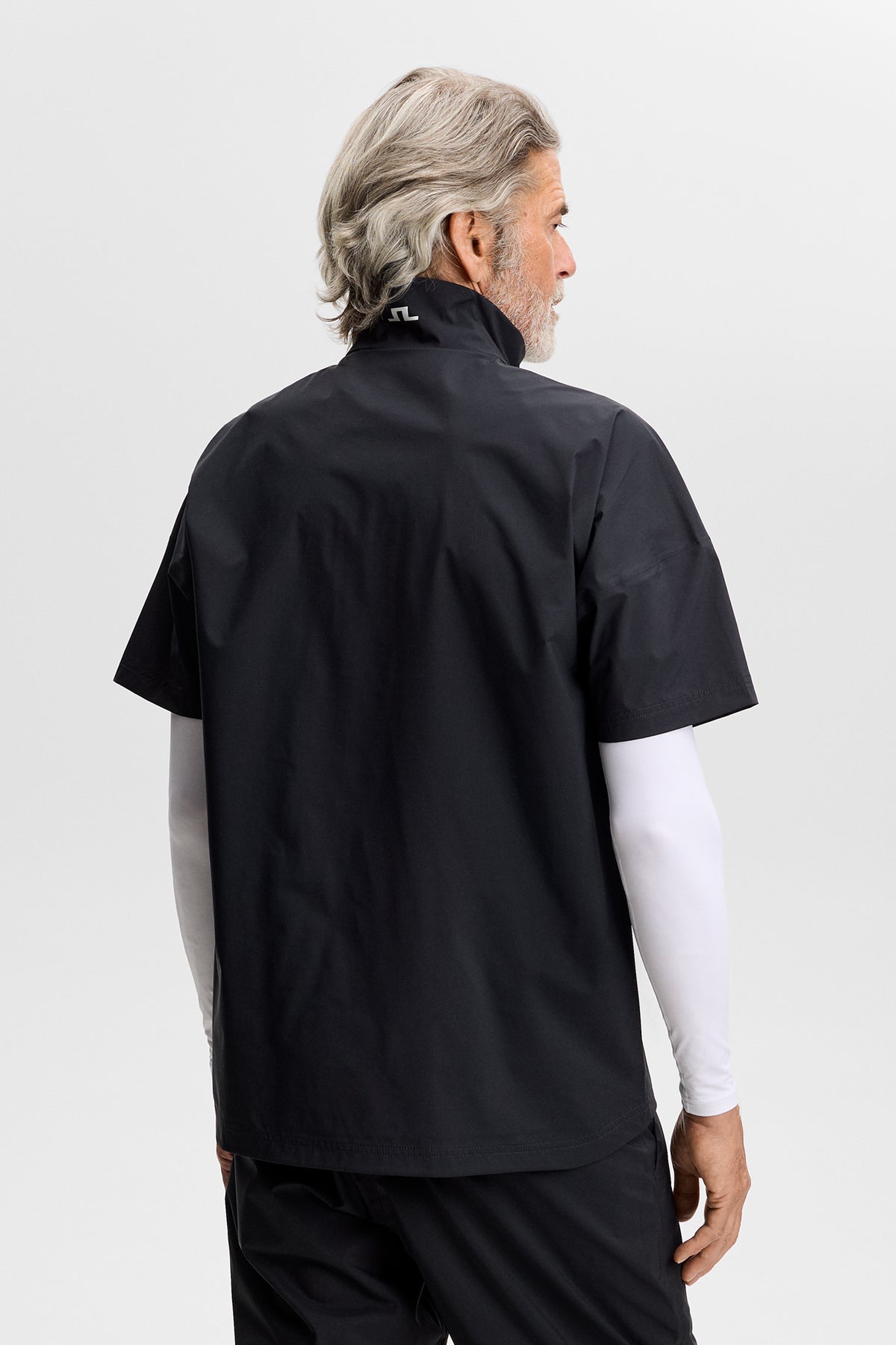 Camisa J.Lindeberg Shay Rain Negra – vista lateral mostrando la silueta aerodinámica y la marca